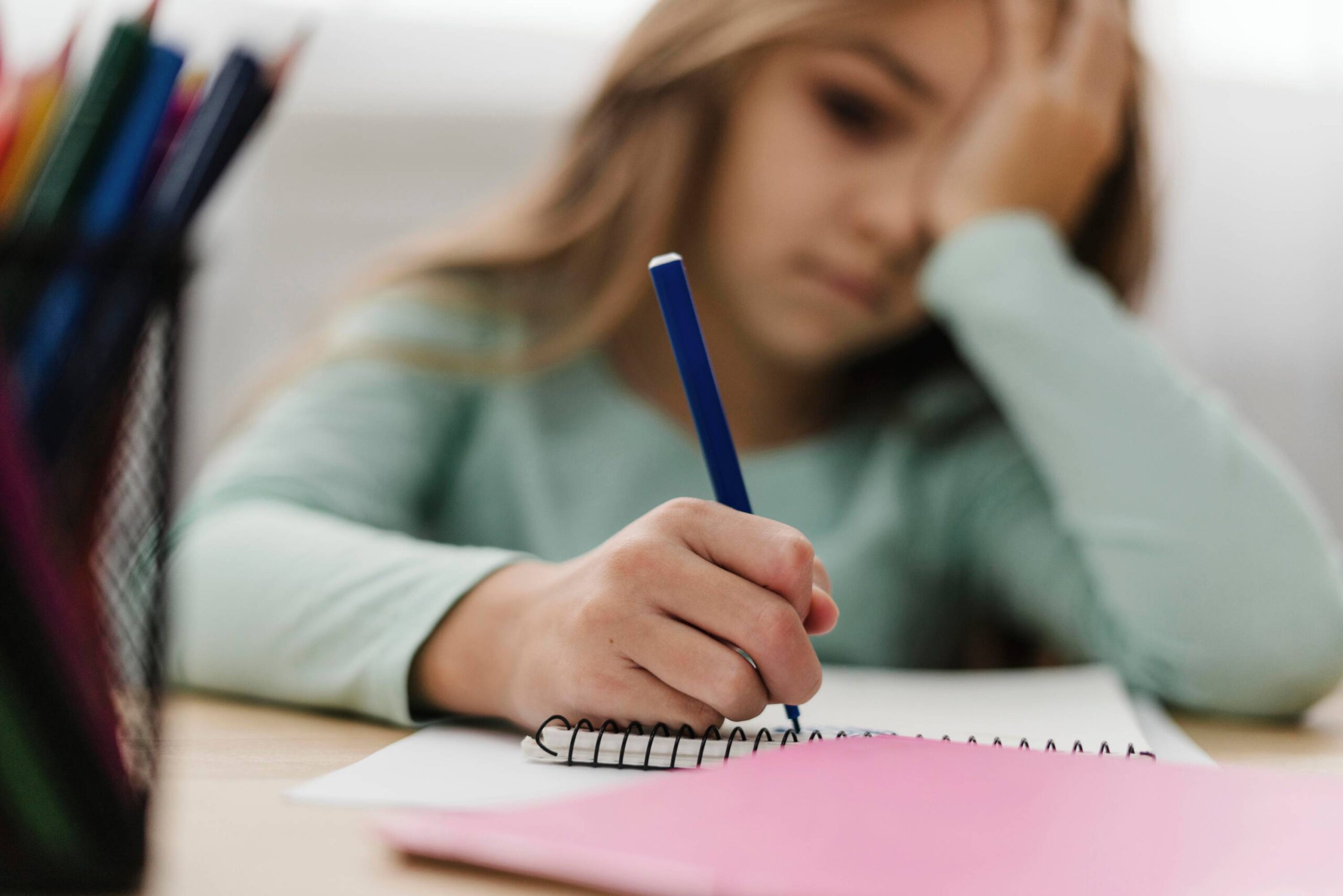 Dziewczynka z trudnością w nauce, siedząca przy biurku z długopisem w ręce